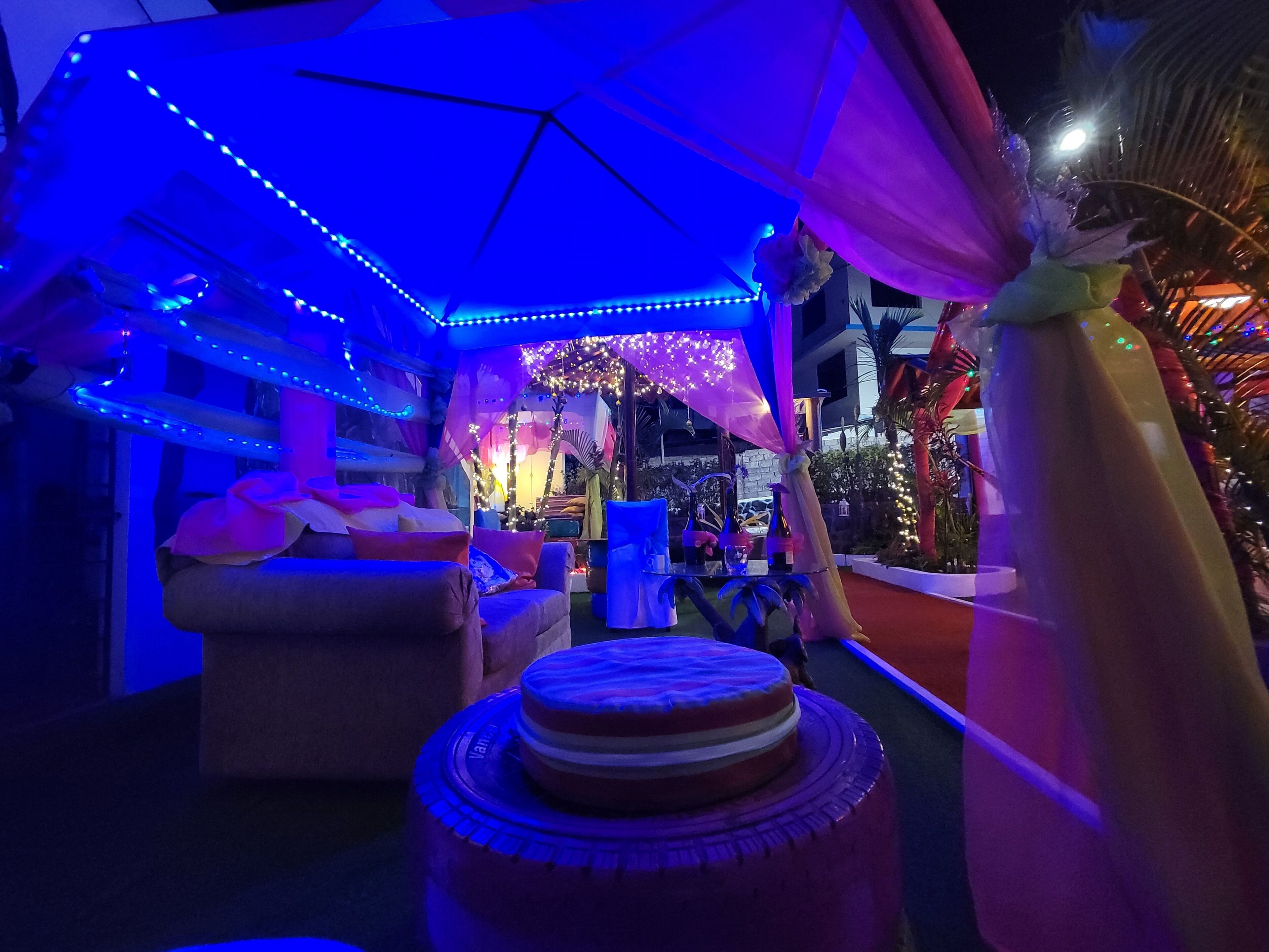 A room with a canopy bed, a round table, and ambient lighting.