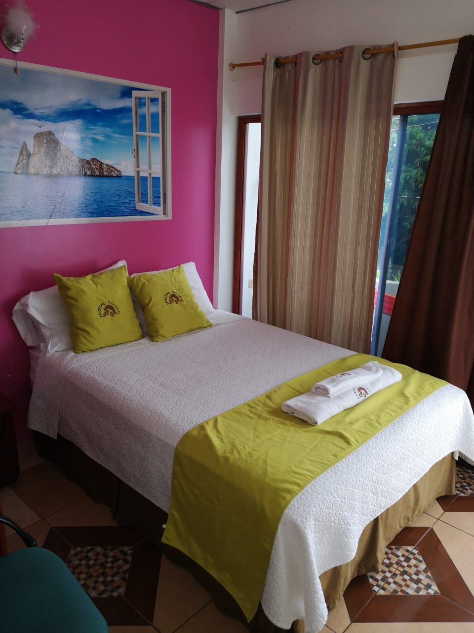 Una cama con una colcha blanca y verde, dos almohadas y una toalla doblada sobre la cama.