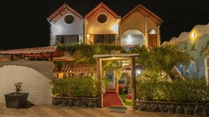 A three-story building with a red-tiled roof, a central circular window, and a mural of sea creatures on the right side. - Hostal Gosén (Puerto Baquerizo Moreno)