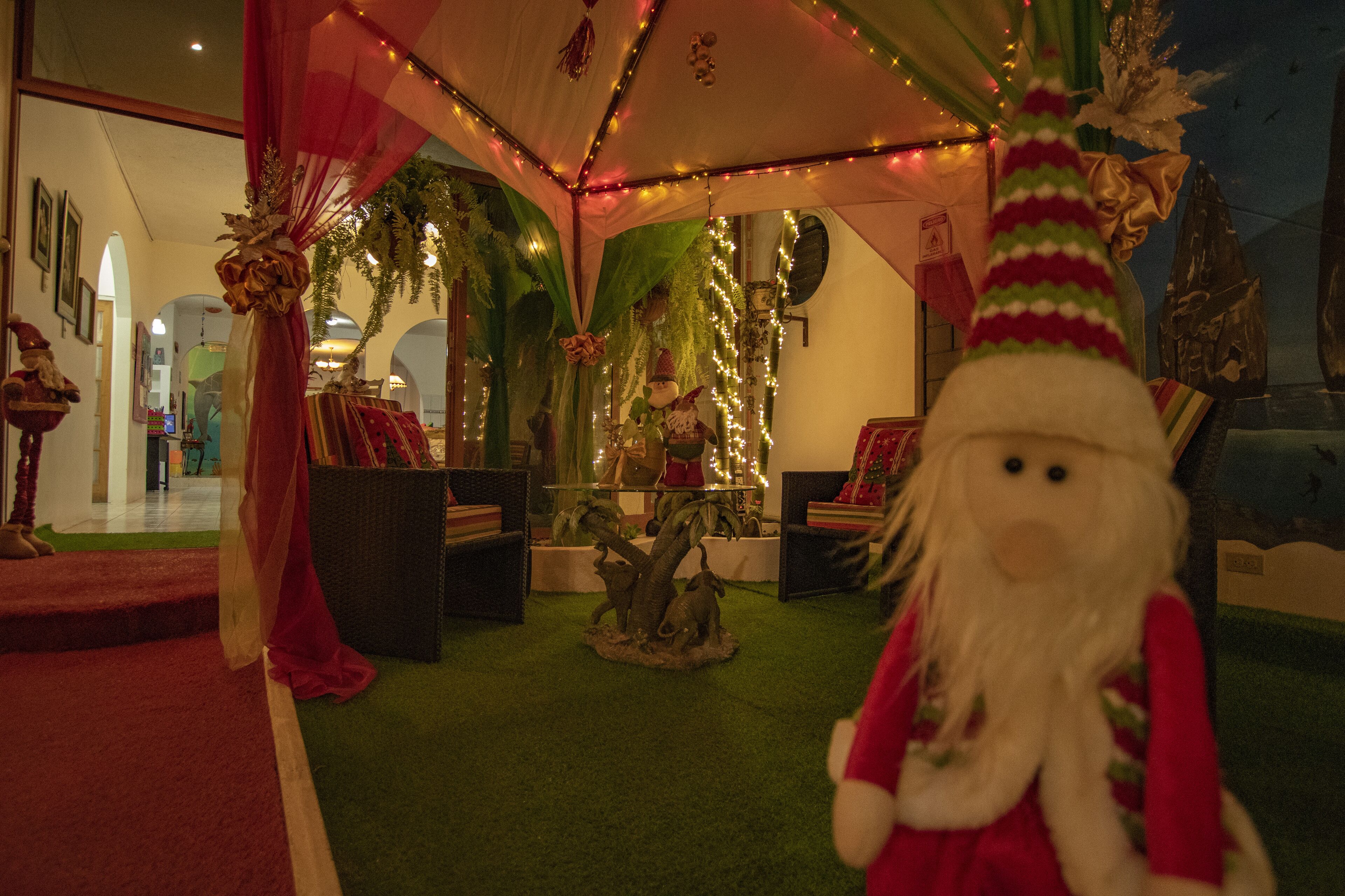 Une pièce décorée d’un sapin de Noël, d’un grand jouet en peluche et d’un tapis rouge.