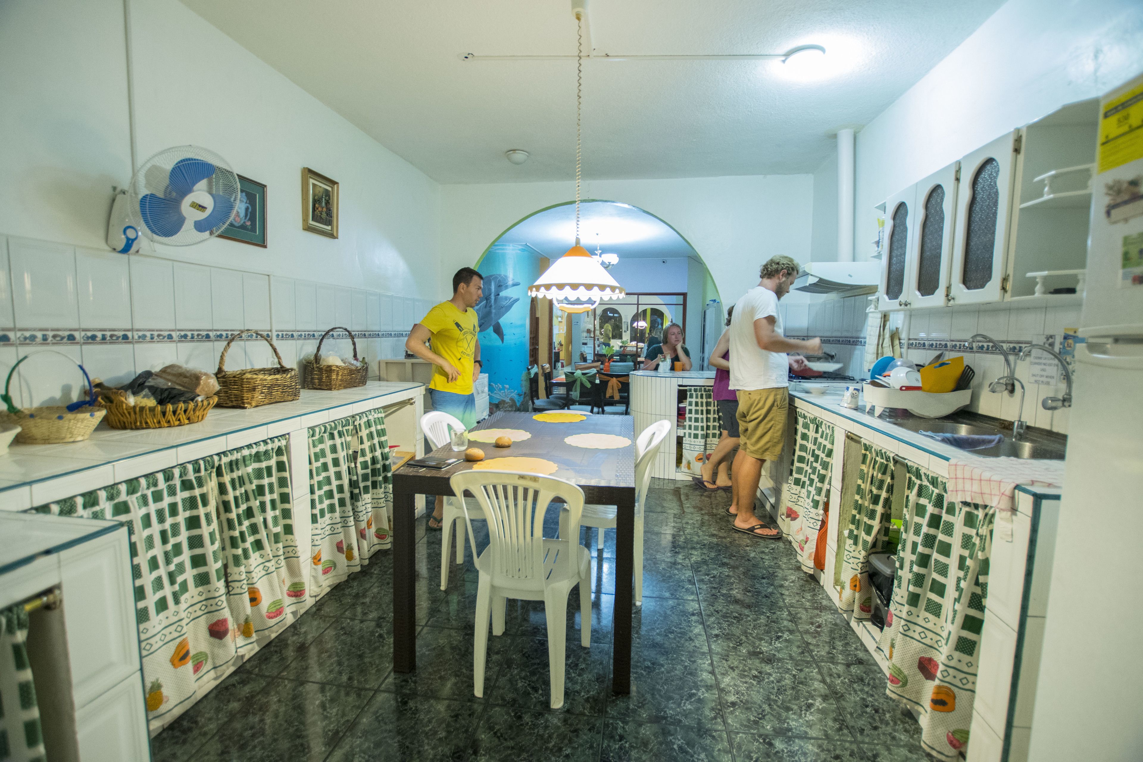A kitchen with a dining table, chairs, and a fan on the wall.