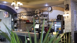 Een bar met een klok, een Pepsi-koelkast en diverse flessen en glazen.