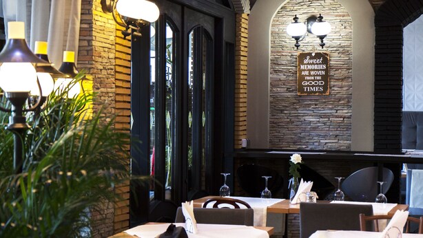 Een restaurantinterieur met bakstenen muren, stenen accenten en gedekte tafels.