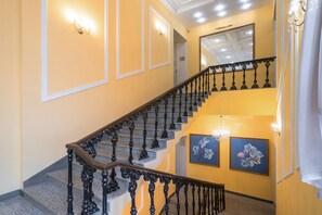 Staircase leads to an upper level with ornate details and framed artworks.