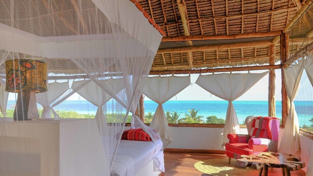 A room with a bed, a chair, and a view of the ocean. - Jua Retreat (Michamvi)