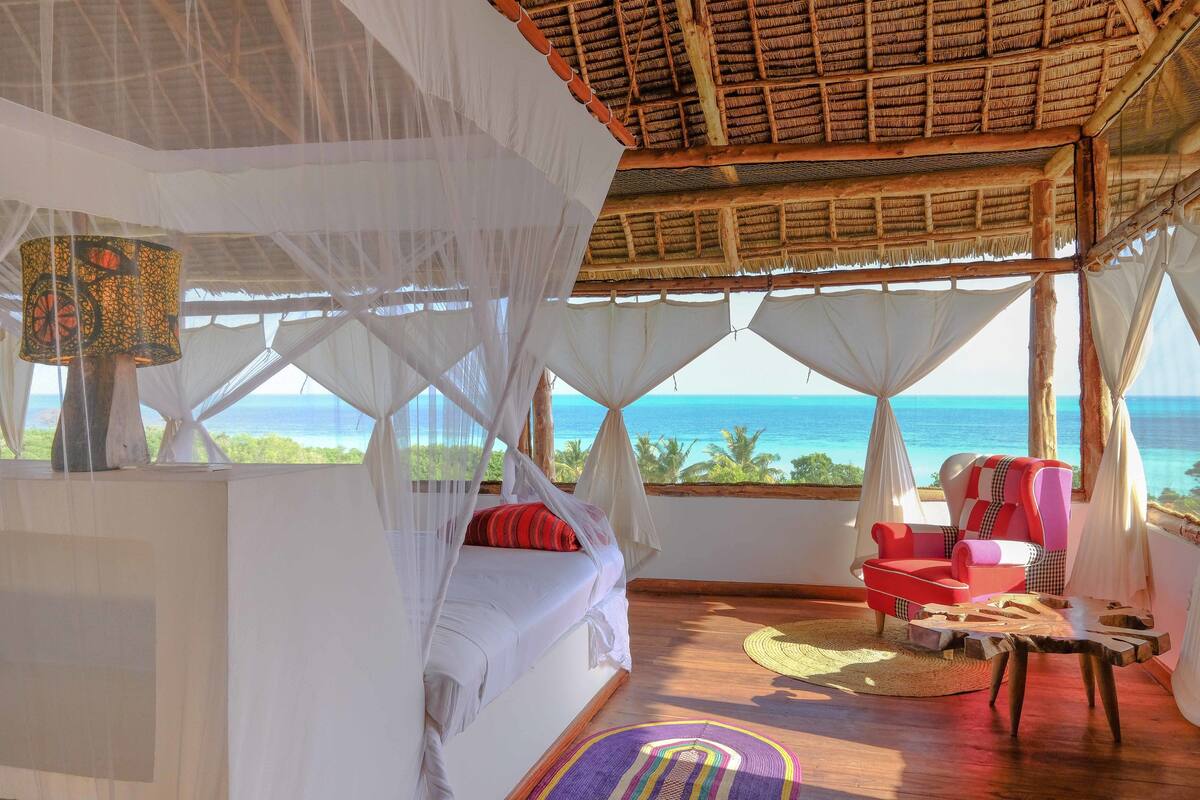 Una habitación con cama, una silla y vista al océano.