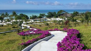 A resort with a pool, lush greenery, and a view of the ocean. - Jua Retreat (Michamvi)