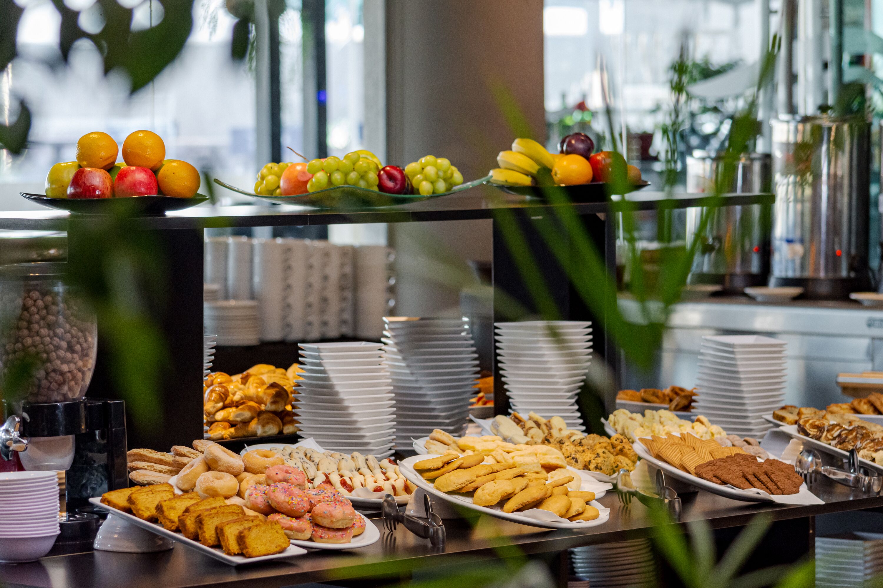 A buffet with various food items including fruits, pastries, and bread.