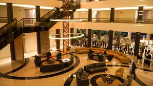 Un vestíbulo espacioso con una zona de estar central, una escalera y vistas del entorno.