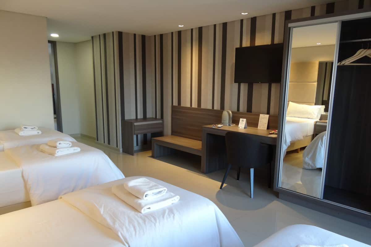 A hotel room with two beds, a desk, a chair, a TV, and a wardrobe.