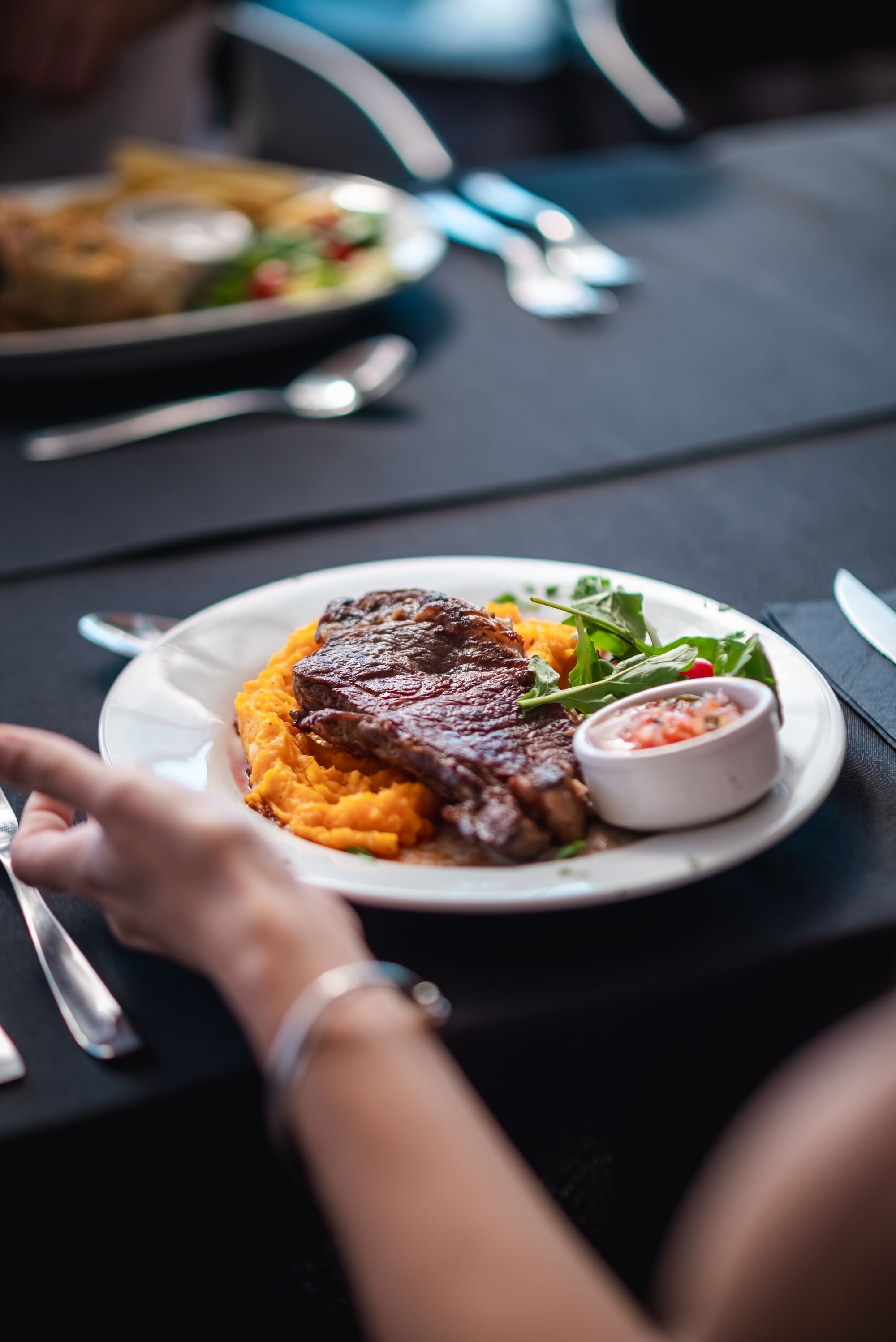 A dining table with a plate of food, a spoon, and a fork.