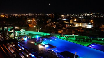 Una piscina techada, una piscina al aire libre, sombrillas