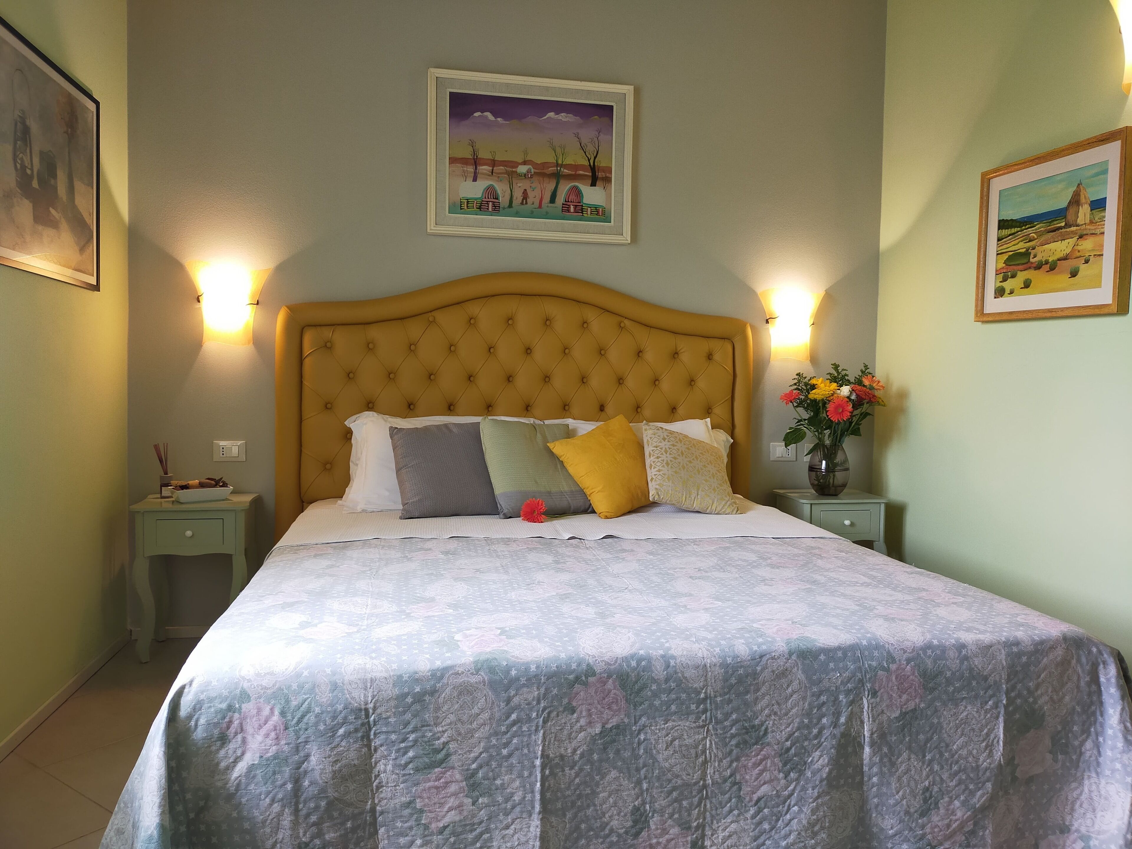 A neatly made bed with a patterned bedspread, two bedside tables with lamps, and framed artwork on the walls.