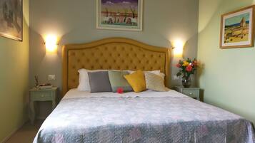 A neatly made bed with a patterned bedspread, two bedside tables with lamps, and framed artwork on the walls.