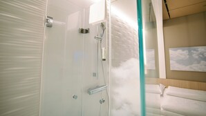 Un baño moderno con cabina de ducha de vidrio, un perchero y un dispensador de toallas de pared.