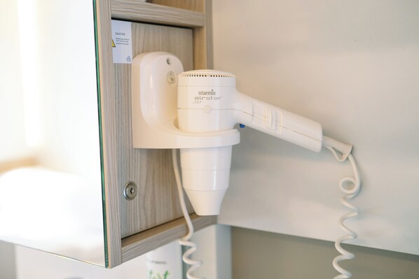 A hair dryer mounted on a wall, connected to a power outlet. - MY CLOUD Transit Hotel (Guests with international flights only) (Frankfurt)