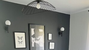 Un dormitorio moderno con una cama grande, paredes grises y obras de arte.