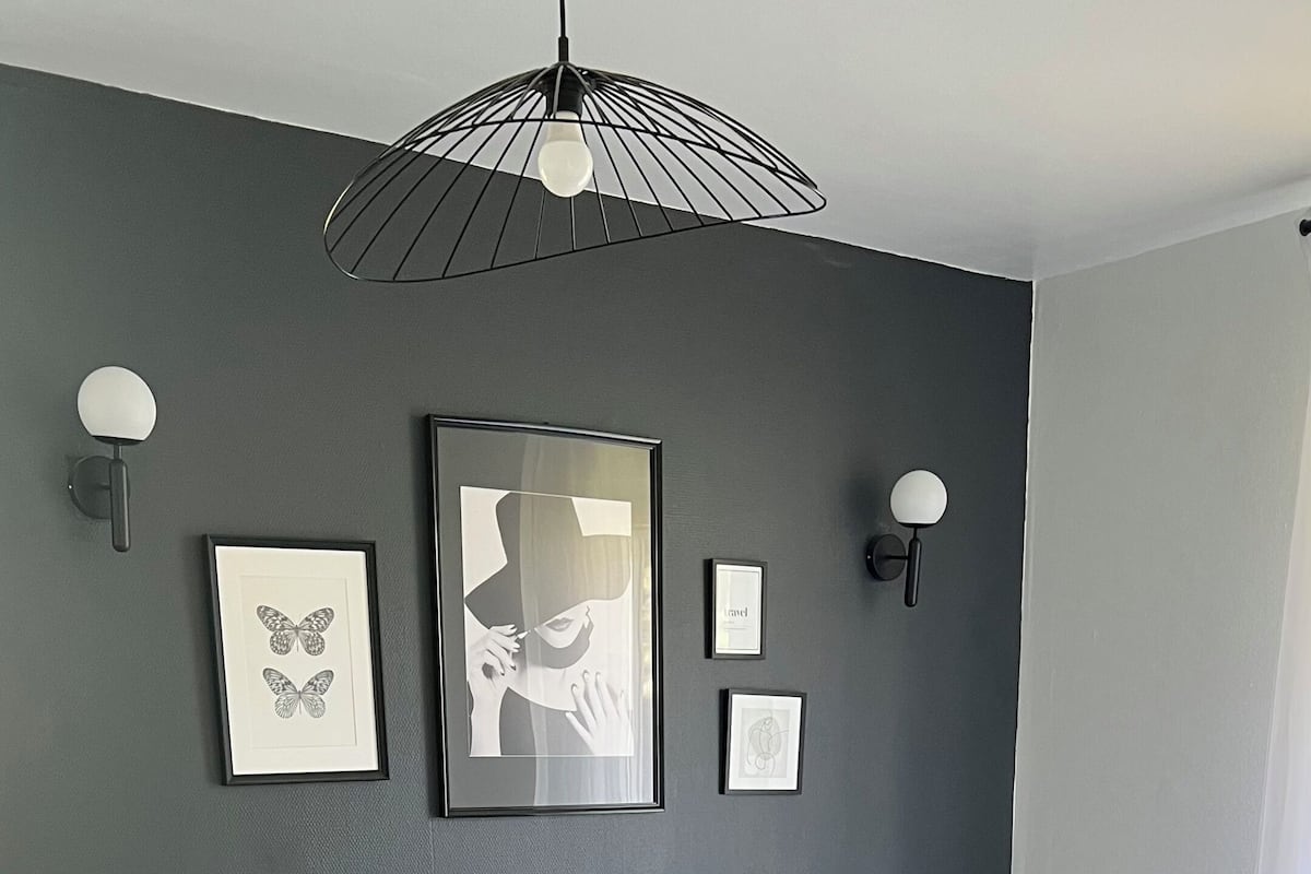A modern bedroom with a large bed, grey walls, and artwork.