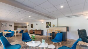 Un interior moderno con sillas azules, mesas blancas y una recepción.