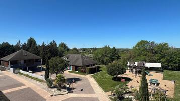 A residential area with two houses, a paved driveway, and a playground with a basketball hoop.