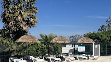 Una piscina al aire libre de temporada, sillones reclinables de piscina