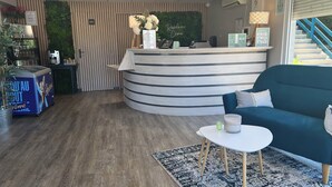 A reception desk with a 'WC' sign, a blue sofa, a small table with a candle, and a blue cooler with 'Crome' branding.