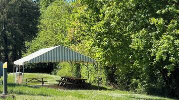 Ein Picknickbereich mit einem Streifen-Canopy und Picknicktischen.