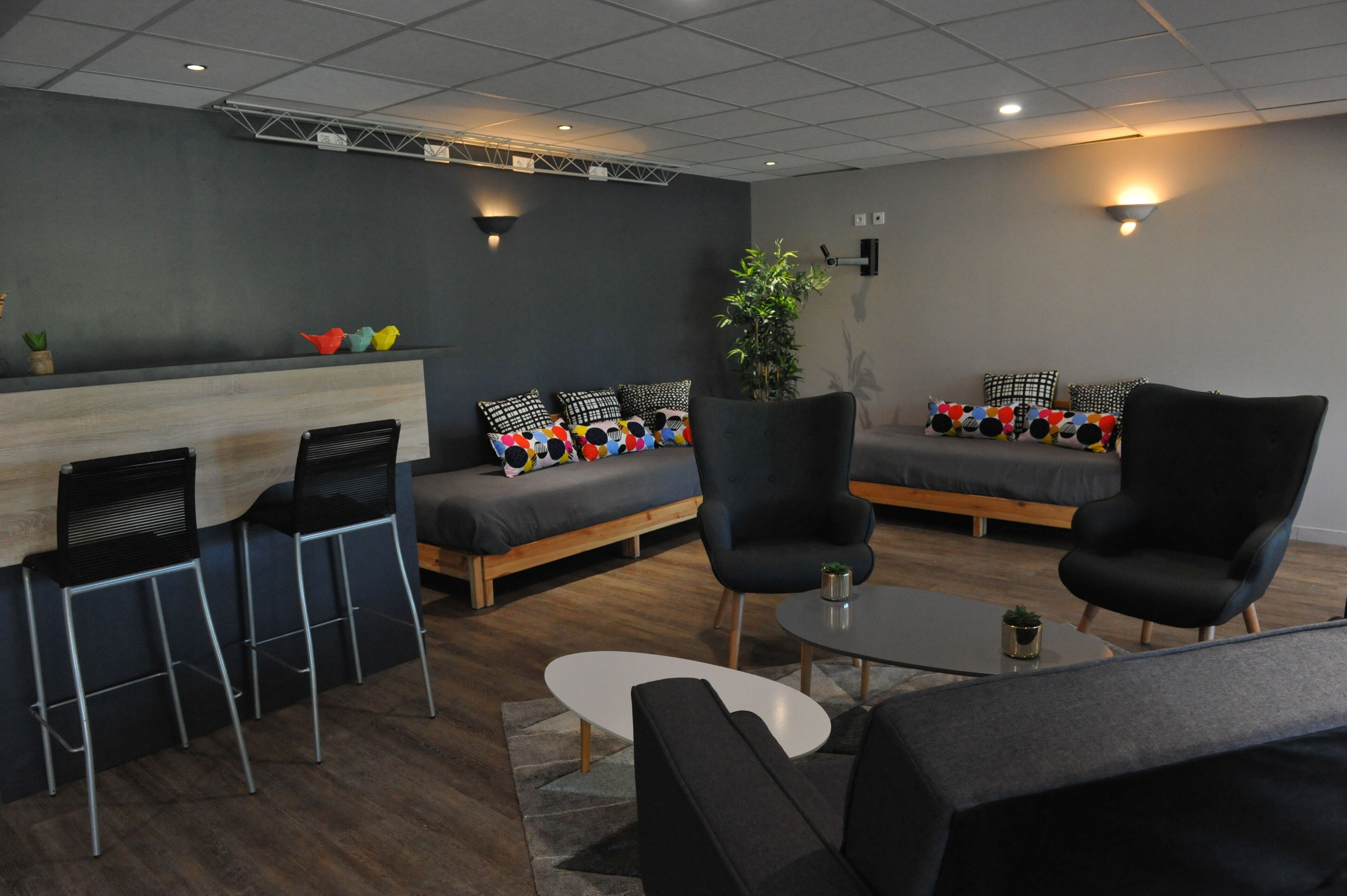 A modern lounge area with a sofa, chairs, a coffee table, and a bar counter.