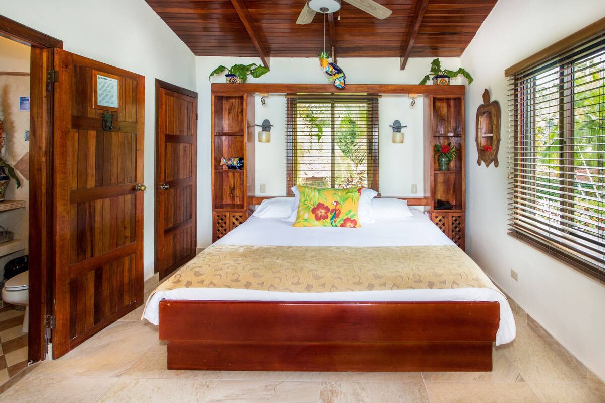 A spacious bedroom with a large bed, wooden headboard, and a ceiling fan.
