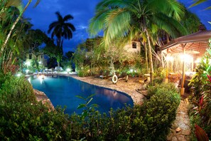 A swimming pool surrounded by lush greenery and palm trees, with a gazebo and lounge chairs in the background. - Villas Nicolás - Adults Only (Quepos)