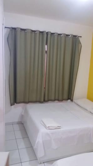 Ein Zimmer mit einem Bett, einem Vorhang und einer weißen Wand.