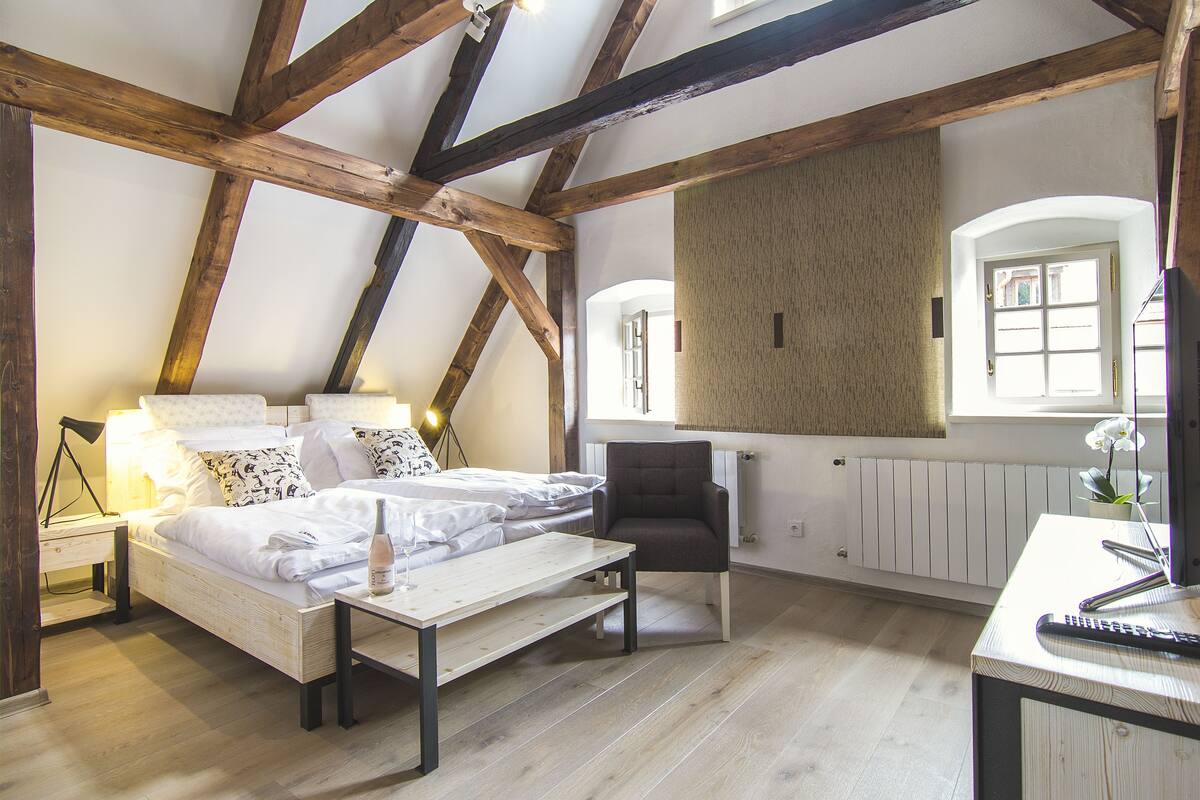 Une chambre avec un plafond en bois, un lit, un bureau et une chaise.
