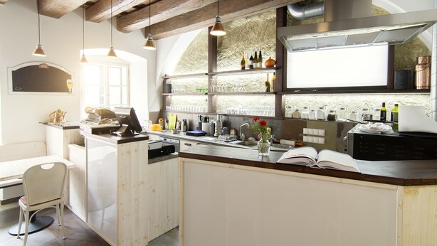 Une cuisine avec des poutres en bois, des luminaires suspendus, un évier et un coin repas comprenant une chaise et une table.