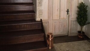 Un escalier en bois mène à un mur de pierres blanches surmonté d’une porte en bois.