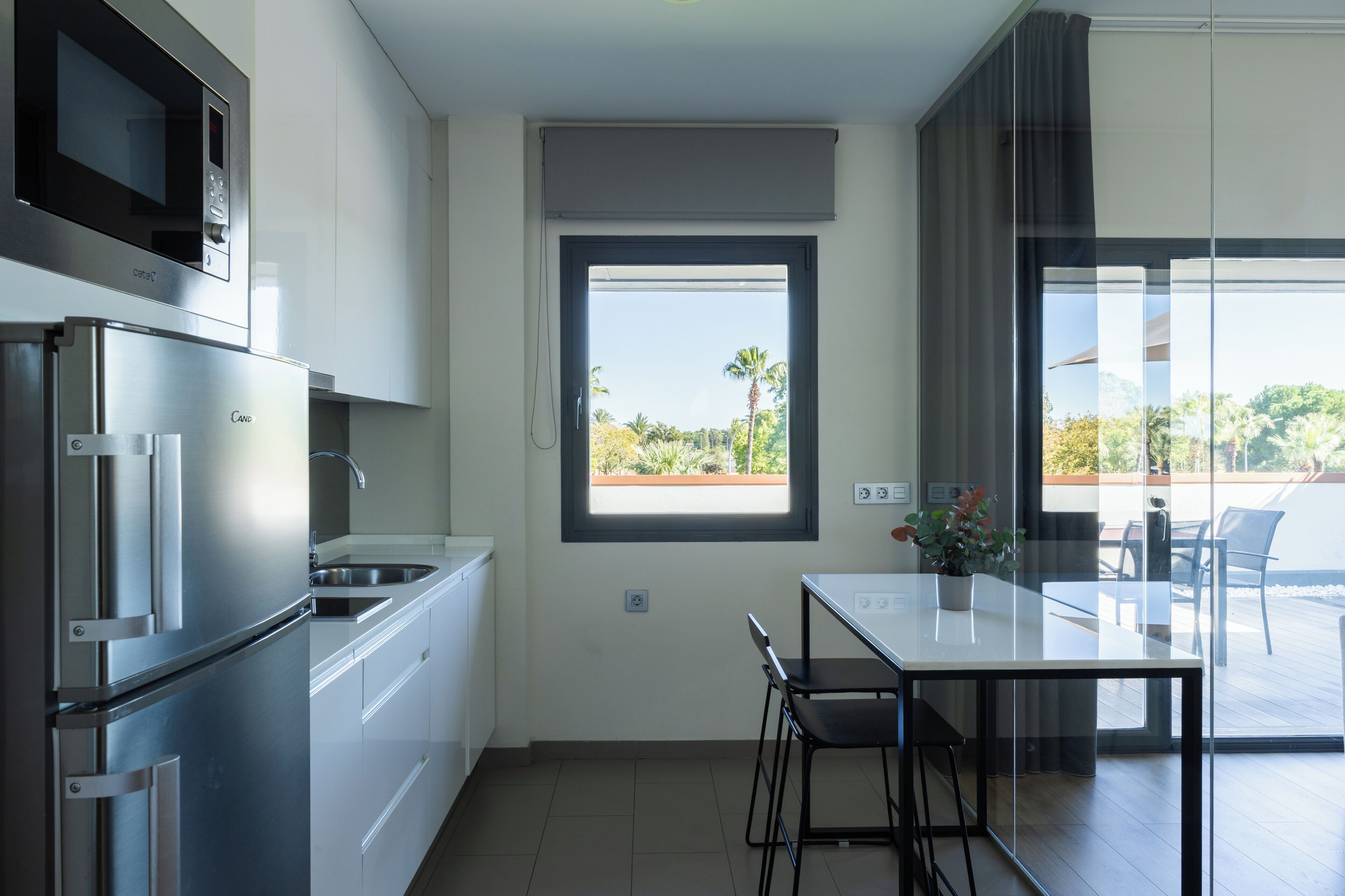 Una cocina moderna con microondas integrado, un refrigerador y ventana con vista a un jardín.