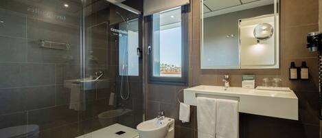 A modern bathroom with a glass-enclosed shower, a bidet, a toilet, and a vanity with a mirror.