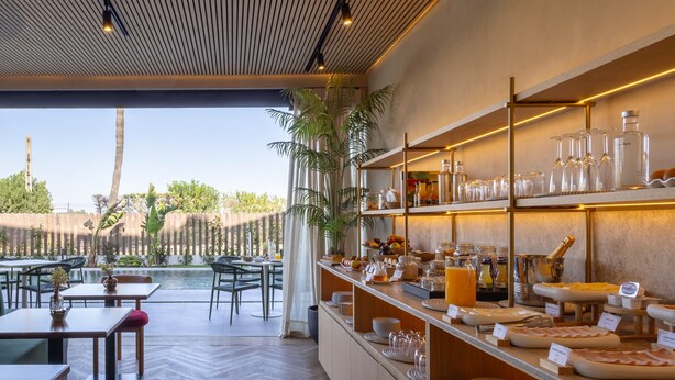 Un restaurante con terraza, una barra de buffet con diferentes opciones de comida y vistas al exterior.