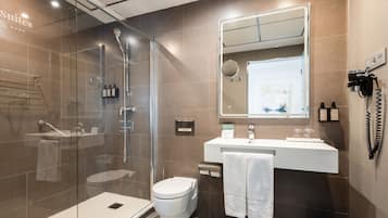 Un baño moderno con ducha de vidrio, inodoro blanco y tocador con espejo.