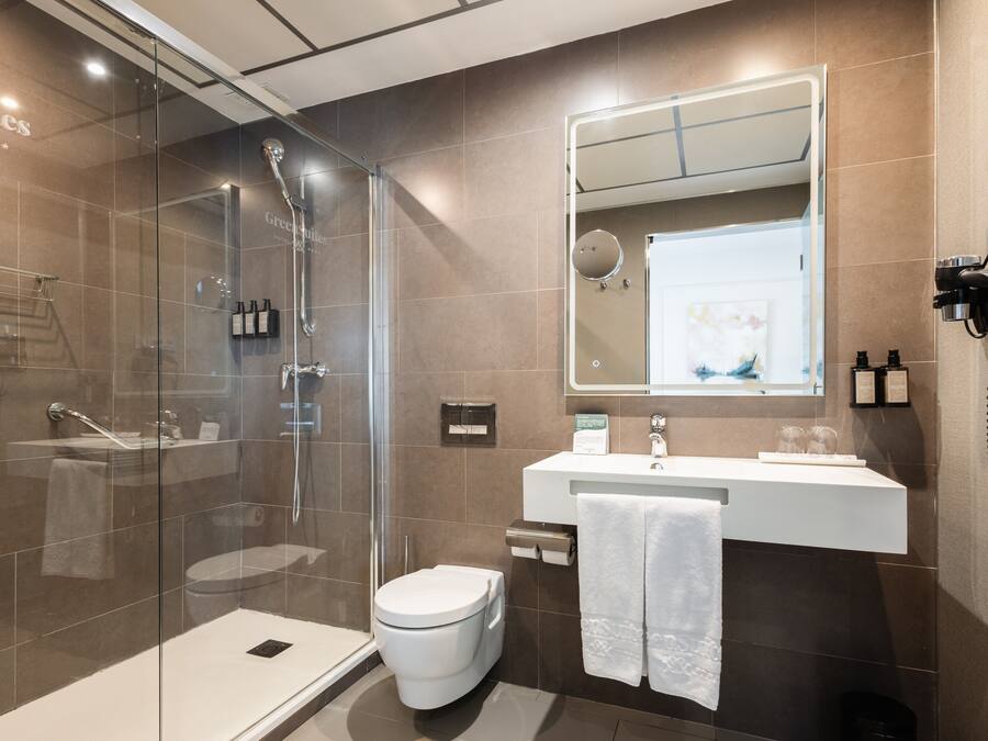 Un baño moderno con ducha de vidrio, inodoro blanco y tocador con espejo.