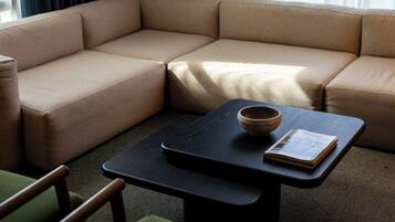Una sala de estar moderna con un sofá seccional color beige, una mesa de centro negra y un sillón verde.