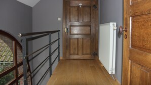 Une porte en bois avec une poignée en métal, un radiateur blanc et une rambarde en métal.