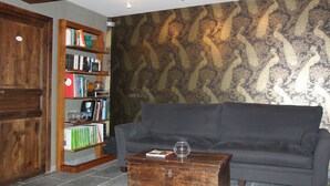 Un salon avec un canapé gris foncé, une bibliothèque en bois et une table basse en bois.