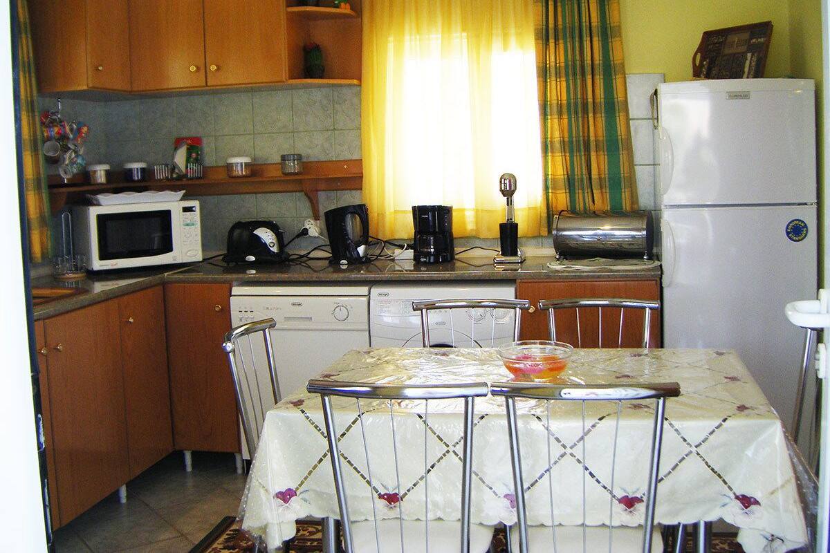 A compact kitchen with wooden cabinets, a microwave, a coffee maker, and a refrigerator.