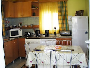 A compact kitchen with wooden cabinets, a microwave, a coffee maker, and a refrigerator.