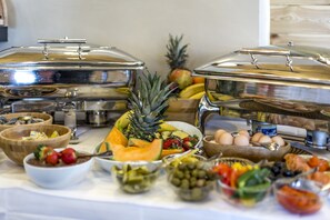 Un bufé con diferentes opciones de comida, incluyendo frutas, verduras y huevos.