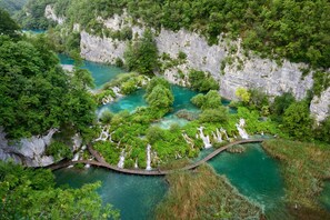Un río con cascadas rodeado de abundante vegetación y acantilados.