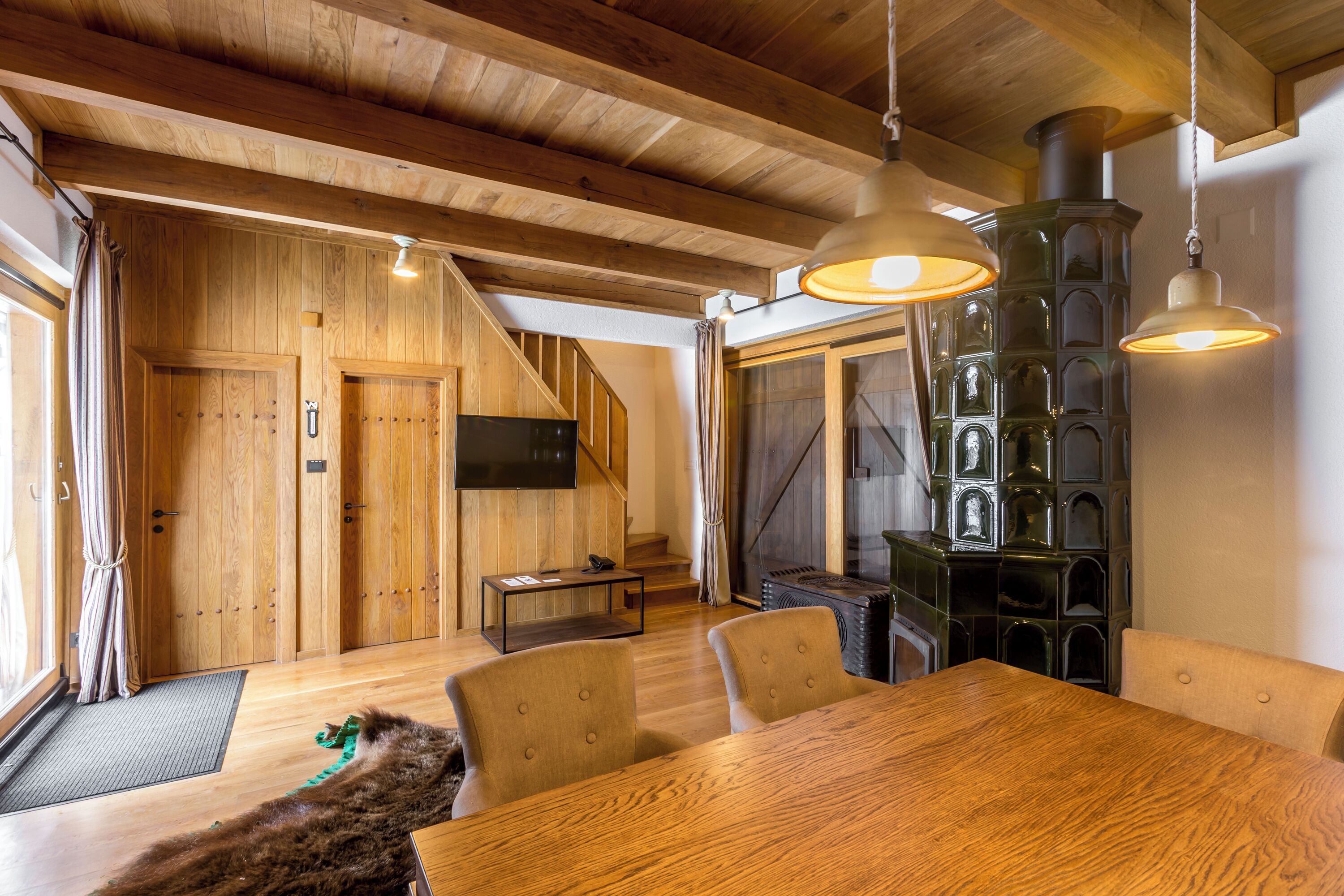A wooden interior with a dining table, chairs, a fireplace, and a staircase.