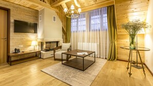 A cozy living room with wooden floors, a fireplace, a TV mounted on the wall, a comfortable sofa, and a coffee table. - Fenomen Plitvice (Plitvicka Jezera)