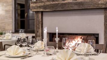 Una mesa de comedor adornada con manteles blancos, copas de cristal y velas.