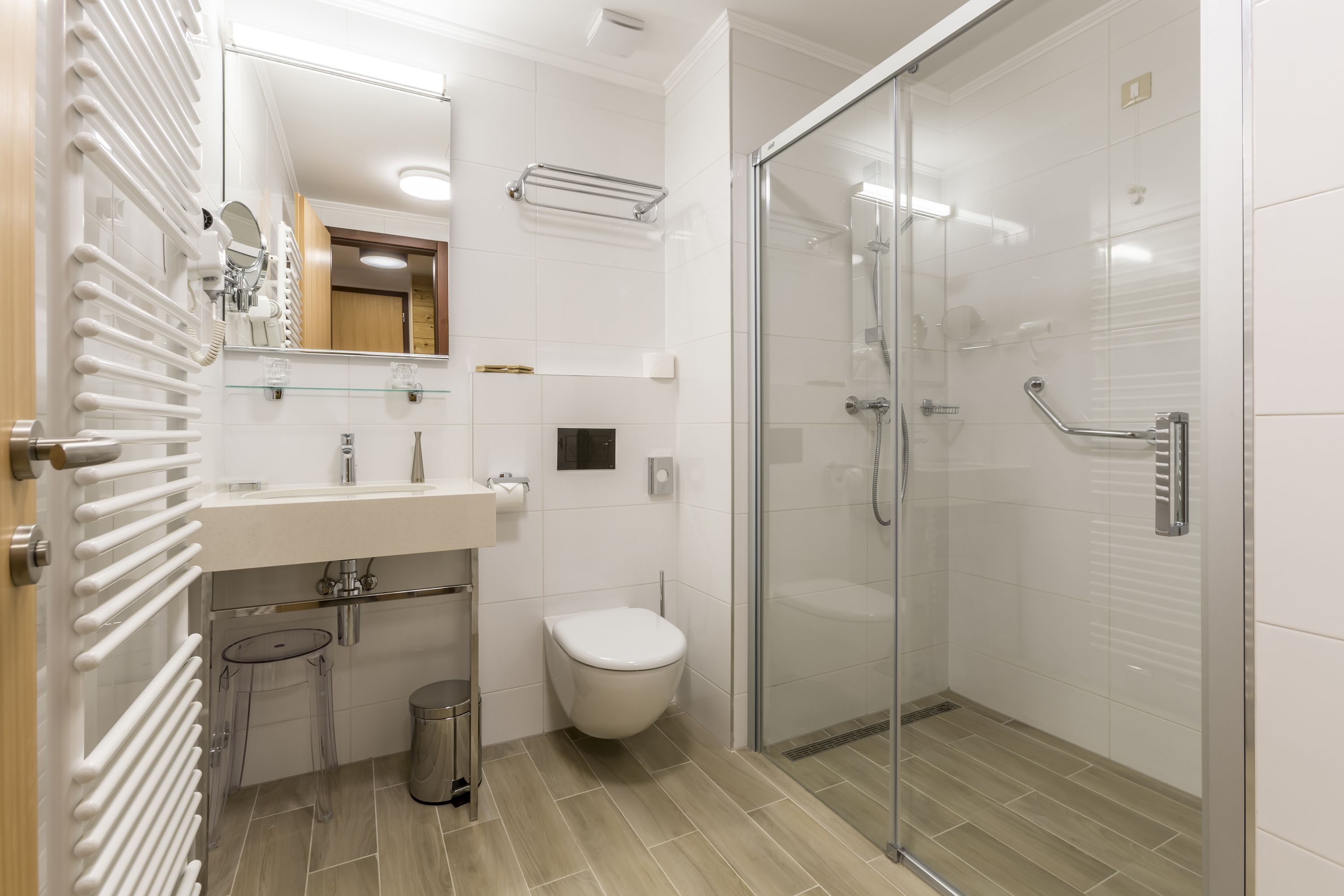 A modern bathroom with a glass shower enclosure, a toilet, and a sink with a mirror above it.